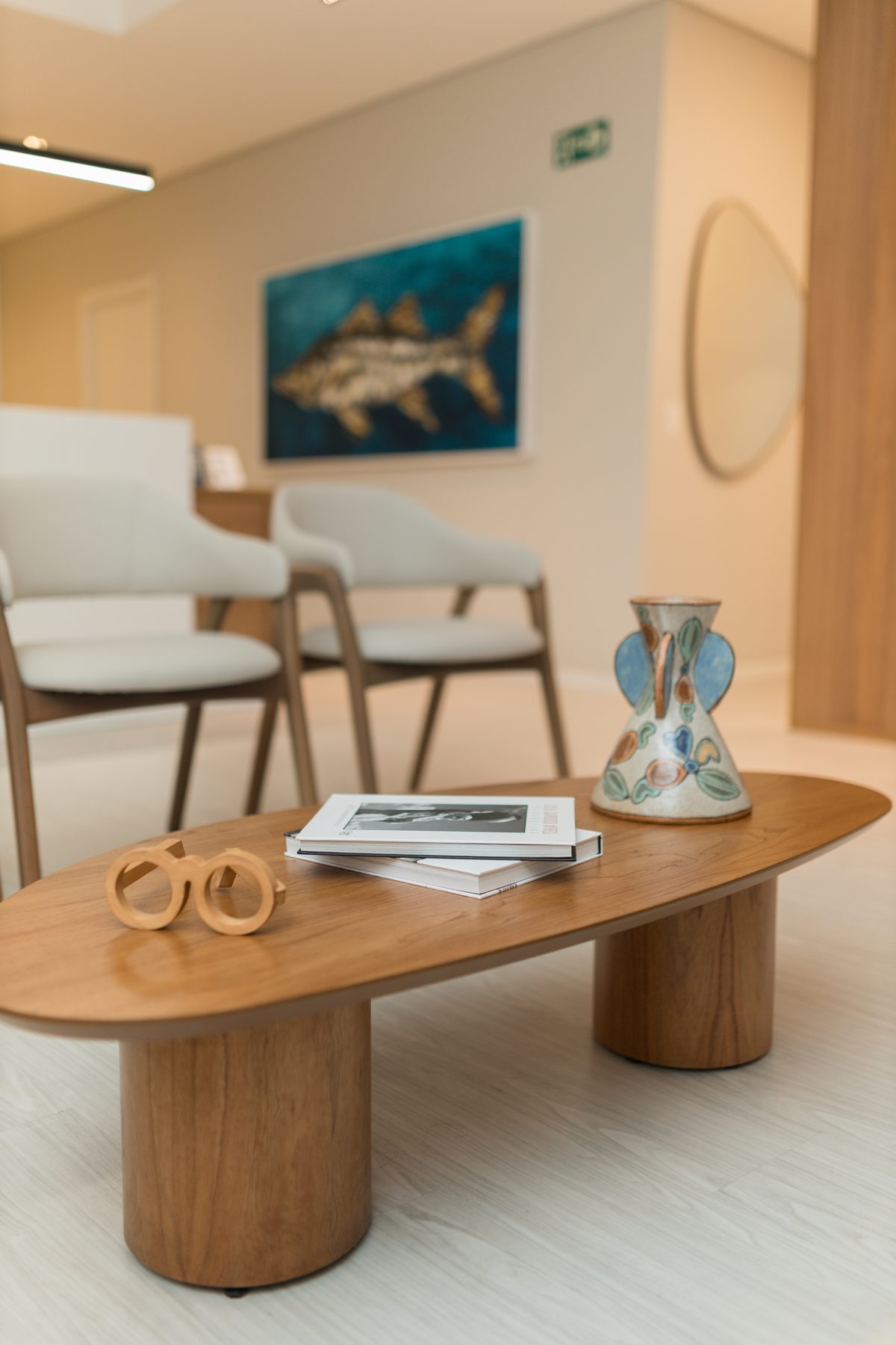 Detalhe da sala de espera da VIW, com mesa de madeira e arte